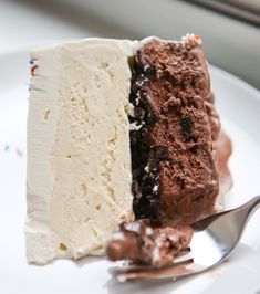 a piece of cake on a white plate with a fork next to it and a window in the background