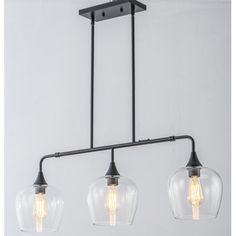 three lights hanging from the ceiling with clear glass globes on each light fixture and black metal frame