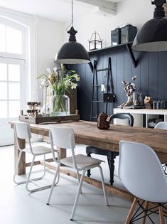 a dining room table with white chairs and hanging lights