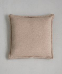 a beige pillow on a white wall