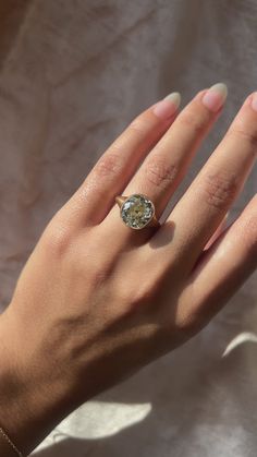 a woman's hand wearing a gold ring with an oval shaped diamond on it