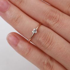 a woman's hand with a diamond ring on top of her finger, against a white background