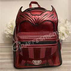 a red leather backpack with horns on the front and back side, sitting on a wooden table