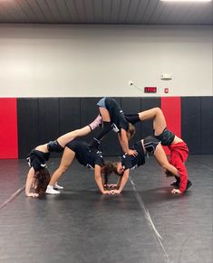 three women doing handstand on one another in a gym