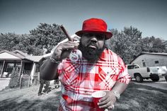 a man with a beard holding a baseball bat and wearing a red hat while standing in front of a house