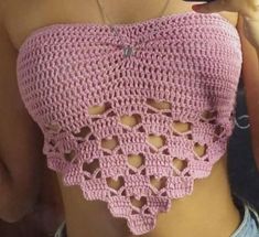 a woman wearing a pink crochet top with cut outs