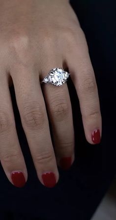 a woman's hand with red nail polish and an engagement ring on her finger