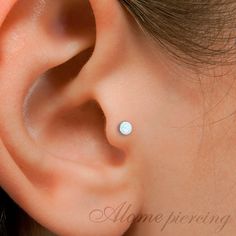 a woman's ear with an opal in the middle and a small white dot on it