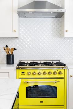 a yellow stove top oven sitting inside of a kitchen next to white cabinets and counter tops