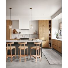 an image of a kitchen setting with bar stools and island in the center area