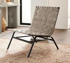 a chair sitting on top of a wooden floor next to a white table and vases