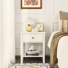 a white nightstand sitting next to a bed in a bedroom