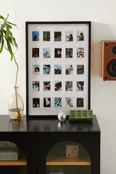 a black cabinet sitting next to a wall with pictures and speakers on top of it