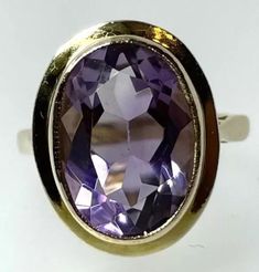 Amethyst Ring Own a piece of vintage charm with this beautiful 9ct yellow gold cocktail ring, featuring a stunning oval amethyst of 4.59 carats. The gemstone is bezel set and the stone and setting measures 17x13.6mm and it is sizeable up to J 1/2.  Crafted in the United Kingdom in 1966, this ring is a timeless piece of fine jewellery that can be worn on special occasions like Mother's Day, Christmas, Graduation, Anniversary, Birthday, and Valentine's Day. This exquisite ring is perfect for colle Classic Amethyst Cabochon Ring For Formal Occasions, Timeless Gold Oval Amethyst Ring, Timeless Oval Gold Amethyst Ring, Timeless Yellow Gold Amethyst Ring With Oval Shape, Classic Amethyst Cabochon Ring For Anniversary, Gold Oval Amethyst Cabochon Ring, Timeless Oval Amethyst Ring For Anniversary, Timeless Oval Amethyst Ring As Gift, Timeless Oval Amethyst Ring For Gift