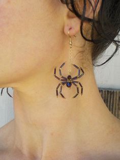 a close up of a woman's neck wearing earrings with a spider on it