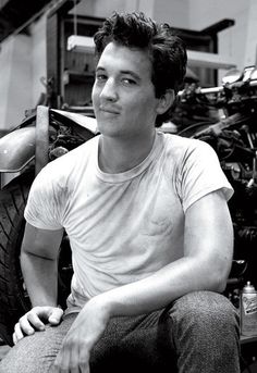 a young man sitting on top of a motorcycle next to a bike tire in a garage