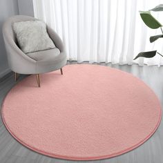 a pink rug in the corner of a room with a chair and window behind it