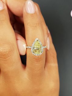 a woman's hand holding a yellow diamond ring