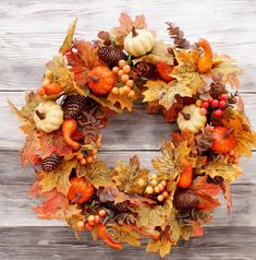 a wreath with autumn leaves, berries and acorns hanging on a wooden wall