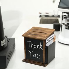 a small wooden box sitting on top of a white table next to a coffee maker