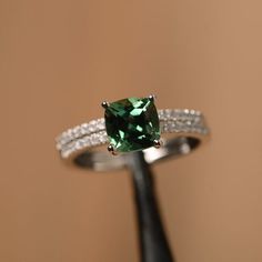 It is a green sapphire ring. The main stone is 7 mm*7 mm cushion cut.weight about 1.94 carats.The basic metal is sterling silver and plated with rhodium/14k white  gold/14k rose gold/14k yellow goldYou can also go to my shop Home for more elegant rings: https://www.etsy.com/shop/godjewelry?ref=hdr_shop_menu Customization is always welcome and please feel free to contact with me if you have any design ideas! Green Sterling Silver Square Cut Ring, Green Sapphire Ring With Sterling Silver, 14k White Gold Cushion Cut Jewelry, Square Cut Diamond Jewelry For May Birthstone, Green Square Cut Diamond Jewelry, Green Cubic Zirconia Asscher Cut Jewelry, Green Asscher Cut Cubic Zirconia Jewelry, 14k White Gold Jewelry With Cushion Cut Center Stone, Green Cubic Zirconia Princess Cut Jewelry