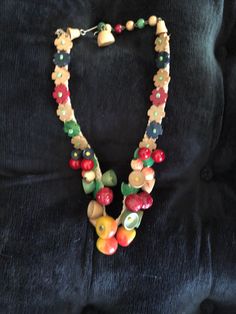 I am offering a whimsical 1950s necklace. This wood fruit and flower necklace is attached to cloth backing. It does have some lucite leaves. It has an adjustable hook and bead closure. It is 15 in. in length. Fruit Necklace Beads, Vintage Necklaces With Wooden Beads, 1950s Necklace, Wood Fruit, Fruit Necklace, Necklace Beads, Flower Necklace, Necklace Etsy, Beaded Necklace