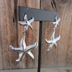 90s silver tone starfish dangle earrings. Textured. Stud backs. Nice quality. Light enough to  be comfy-- one weighs the equivalent of a quarter (coin). They are 2-3/8" long x 1-3/8" wide at widest part No noted flaws. Nickel-free Silver Starfish Earrings, Nickel Free Silver Starfish Earrings, Silver Ocean-inspired Earrings With Starfish Charm, Ocean-inspired Silver Earrings With Starfish Charm, Silver Drop Earrings With Starfish Charm, Nautical Star, Fish Earrings, Resort Chic, Star Fish