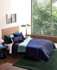 a bed room with a neatly made bed next to a window and a green rug