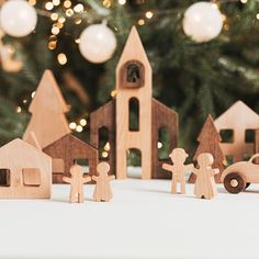 wooden toy figures standing in front of a christmas tree