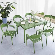 a green table and chairs sitting on top of a white tile floor next to a potted plant