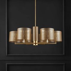 an elegant chandelier in gold with shades on the lampshade and black walls