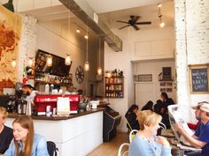 people sitting at tables in a restaurant with food on the counter and ceiling fans hanging from the ceiling