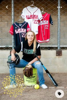 a woman kneeling down next to a baseball bat and ball in front of some t - shirts