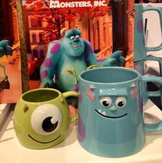 two monsters mugs sitting next to each other on a table with an advertisement behind them