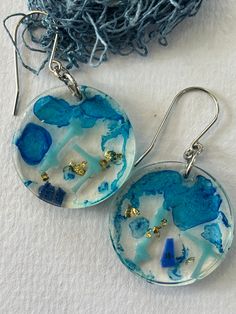 These lightweight earrings have been made with pieces of beach plastic, flakes of gold leaf and translucent blue dye.  This has all been set in a plant based resin [ 77% bio based] to keep it all as environmentally friendly as possible. I have used stainless steel findings.  The resin and beach plastic feature measures 3 cm in diameter. Blue Dangle Earrings With Ocean-inspired Style, Ocean-inspired Blue Dangle Earrings, Cadmium-free Blue Earrings As Gift, Handmade Blue Ocean-inspired Earrings, Blue Dangle Earrings Cadmium-free, Blue Cadmium-free Drop Earrings, Unique Blue Jewelry With Natural Inclusions, Ocean-inspired Blue Earrings With Ear Wire, Ocean-inspired Blue Earrings For Gifts