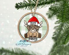 a christmas ornament hanging from a tree with a buffalo wearing a santa hat