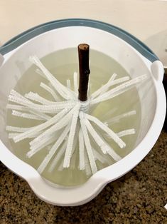 a large white bowl filled with liquid and sticks sticking out of the water in it