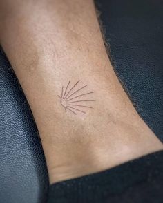 a small tattoo on the ankle of a man's foot, which is shaped like a sunburst