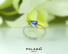 a close up of a ring on a table with flowers in the background and text that reads polama