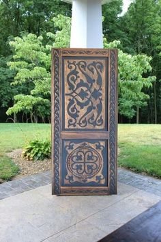 an intricately carved wooden panel on the side of a building with trees in the background