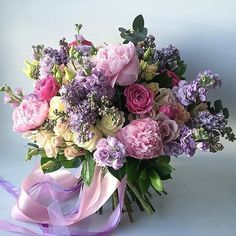 a bouquet of pink and purple flowers on a white background with a purple ribbon around it