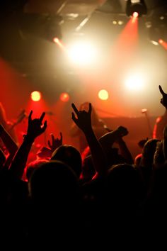 a crowd of people at a concert with their hands in the air and lights on