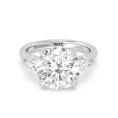 This ring's design will speak to a bride-to-be who wants a sparkler that's seriously glam. This three-stone engagement ring boasts a 6-carat diamond center stone flanked by pear-shaped side stones. The central gem is held by claw prongs and supported by an angular gallery. Peeking from underneath the center stone is a bonus diamond for extra sparkle. Luxury Pear-shaped Three Stone Rings, Luxury Trillion Cut Three Stone Diamond Ring, Luxury Three Stone Trillion Cut Diamond Ring, Trillion Cut Diamond Ring For Wedding, Fine Jewelry Pear-shaped Three Stone Diamond Ring, Fine Jewelry Three-stone Pear-shaped Diamond Ring, Pear-shaped Three Stone Diamond Ring, White Marquise Cut Three Stone Diamond Ring, Trillion Cut Platinum Diamond Wedding Ring