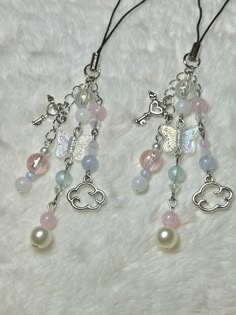 two necklaces with charms and beads on a white furnishing area, one has a butterfly charm attached to it