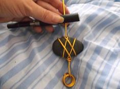 a person holding a pair of scissors on top of a piece of cloth with wire attached to it