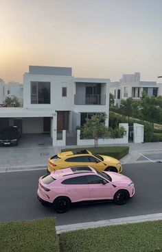 three different colored cars parked in front of some white and black houses at sunset or dawn