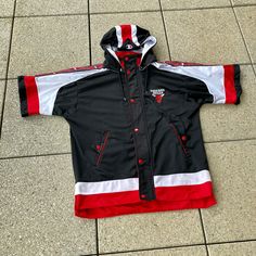 a black and red jacket laying on the ground next to a tile floor with white stripes