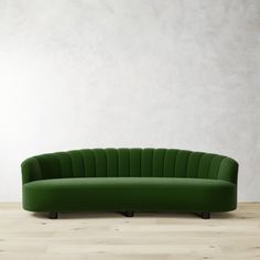 a green couch sitting on top of a wooden floor next to a white wall in an empty room