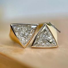 two gold and white diamond earrings sitting on top of a table