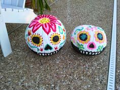 two decorated sugar skulls sitting on the ground